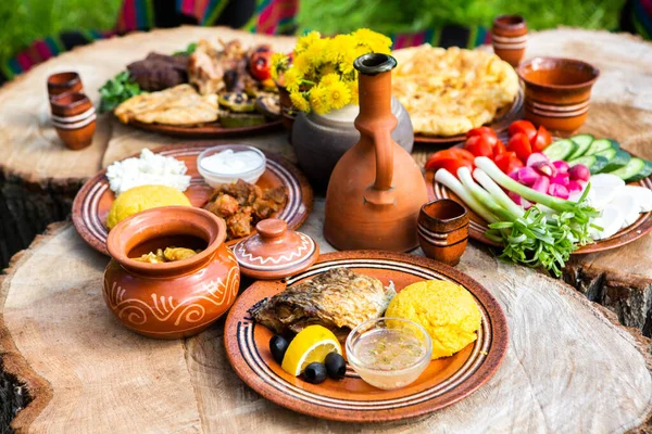 Kamp yaparken ızgara et, polenta ve sebze tabağı ile ev yapımı Romen yemekleri. Ahşap masanın üzerinde romantik Moldova yemekleri.