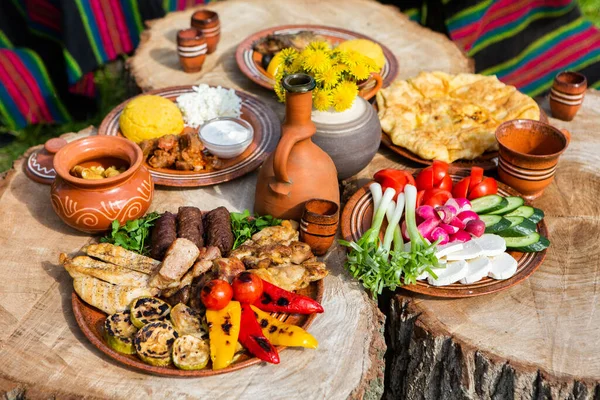 Kamp yaparken ızgara et, polenta ve sebze tabağı ile ev yapımı Romen yemekleri. Ahşap masanın üzerinde romantik Moldova yemekleri.