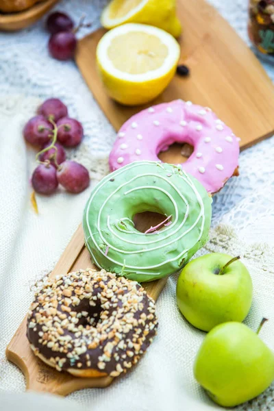 Outdoors picnic in a lush green park with a tasty croissant, fruits, donuts and wine on grass. Summer picnic on the blanket.