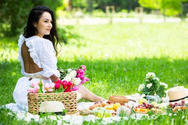 Güzel esmer kadın parkta piknik battaniyesinde dinleniyor. Doğada dinlenmek..
