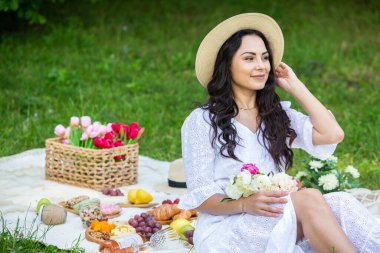 Güzel esmer kadın parkta piknik battaniyesinde dinleniyor. Doğada dinlenmek..