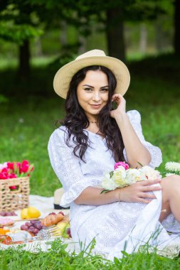 Güzel esmer kadın parkta piknik battaniyesinde dinleniyor. Doğada dinlenmek..