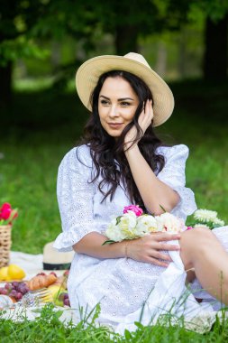 Güzel esmer kadın parkta piknik battaniyesinde dinleniyor. Doğada dinlenmek..