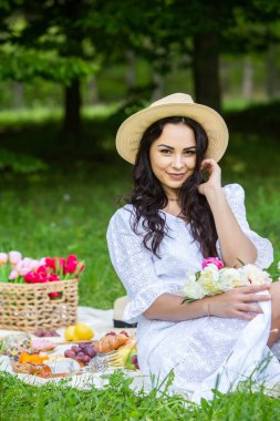 Güzel esmer kadın parkta piknik battaniyesinde dinleniyor. Doğada dinlenmek..