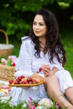 Güzel esmer kadın parkta piknik battaniyesinde dinleniyor. Doğada dinlenmek..