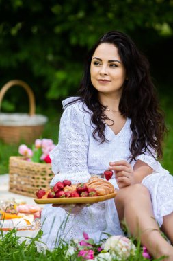 Güzel esmer kadın parkta piknik battaniyesinde dinleniyor. Doğada dinlenmek..