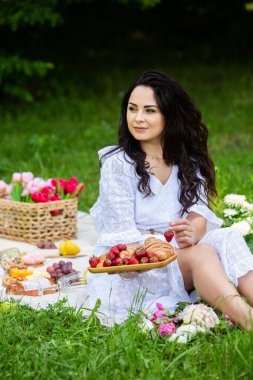 Güzel esmer kadın parkta piknik battaniyesinde dinleniyor. Doğada dinlenmek..