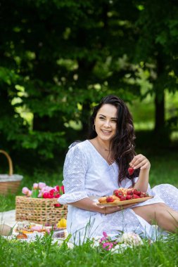 Güzel esmer kadın parkta piknik battaniyesinde dinleniyor. Doğada dinlenmek..