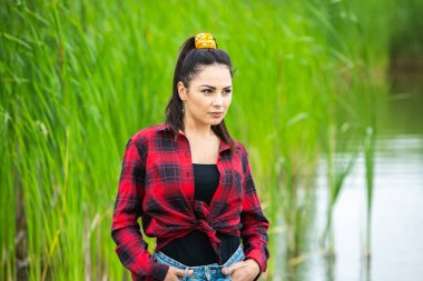 Esmer kız, nehirde lastik çizmelerle eğleniyor. Göldeki genç kadın hayatın tadını çıkar.