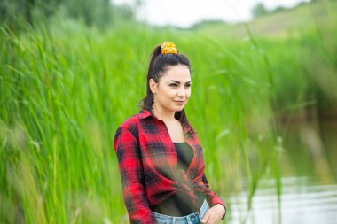 Esmer kız, nehirde lastik çizmelerle eğleniyor. Göldeki genç kadın hayatın tadını çıkar.