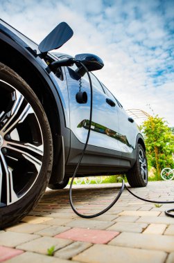 Elektrikli araç şarj istasyonu. Kırsal bir evin önünde elektrikli araba fişi takmak..