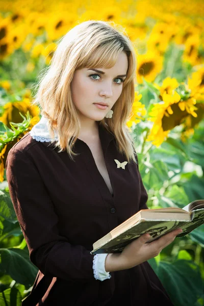 Retrato de estudante russa lendo um livro no campo de girassol — Fotografia de Stock