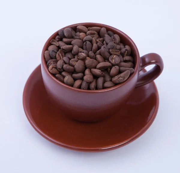 Tasse à café avec soucoupe pleine de grains de café torréfiés — Photo