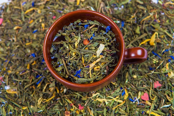 Niveles de té verde seco en la taza marrón — Foto de Stock