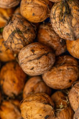 walnuts and kernels captured in a rustic natural setting. Some nuts are cracked open, revealing the rich interior texture, while others remain whole on a dark wooden surface. 