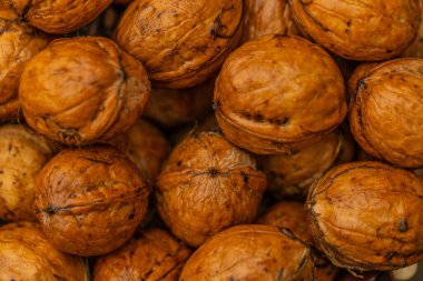 walnuts and kernels captured in a rustic natural setting. Some nuts are cracked open, revealing the rich interior texture, while others remain whole on a dark wooden surface. 