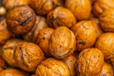 walnuts and kernels captured in a rustic natural setting. Some nuts are cracked open, revealing the rich interior texture, while others remain whole on a dark wooden surface. 