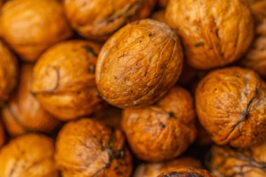 walnuts and kernels captured in a rustic natural setting. Some nuts are cracked open, revealing the rich interior texture, while others remain whole on a dark wooden surface. 