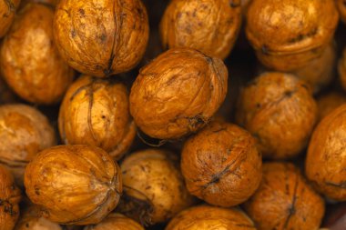 walnuts and kernels captured in a rustic natural setting. Some nuts are cracked open, revealing the rich interior texture, while others remain whole on a dark wooden surface. 