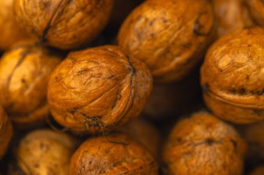 walnuts and kernels captured in a rustic natural setting. Some nuts are cracked open, revealing the rich interior texture, while others remain whole on a dark wooden surface. 