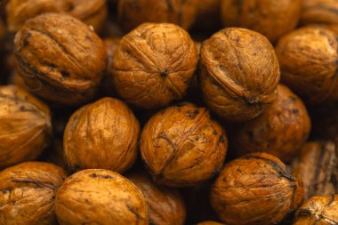 walnuts and kernels captured in a rustic natural setting. Some nuts are cracked open, revealing the rich interior texture, while others remain whole on a dark wooden surface. 