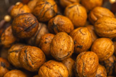 walnuts and kernels captured in a rustic natural setting. Some nuts are cracked open, revealing the rich interior texture, while others remain whole on a dark wooden surface. 
