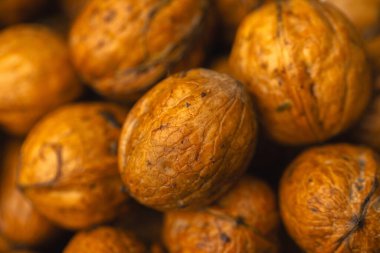 walnuts and kernels captured in a rustic natural setting. Some nuts are cracked open, revealing the rich interior texture, while others remain whole on a dark wooden surface. 