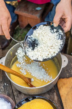 Kırsal Polenta 'yı Koyun Peyniri ile Açık Ateş' e Hazırlayan Adam. Otantik Taşra Yemekleri. Kırsal Doğa Yemekleri. Geleneksel köy mutfağı. Kalıtsal Gıda Sahnesi