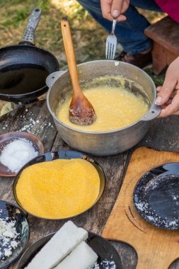 Kırsal Polenta 'yı Koyun Peyniri ile Açık Ateş' e Hazırlayan Adam. Otantik Taşra Yemekleri. Kırsal Doğa Yemekleri. Geleneksel köy mutfağı. Kalıtsal Gıda Sahnesi