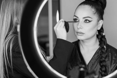 Zarif gözleri, canlı sanatsal makyajı ve fütüristik saç tasarımı olan zarif bir kadının yakın plan portresi. Renkli, yaratıcı makyajlı, desenli saç stili ve dramatik ışıklandırmalı genç bir kadının moda güzelliği.