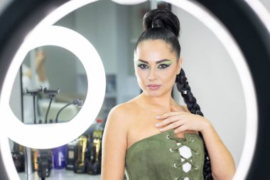 Zarif gözleri, canlı sanatsal makyajı ve fütüristik saç tasarımı olan zarif bir kadının yakın plan portresi. Renkli, yaratıcı makyajlı, desenli saç stili ve dramatik ışıklandırmalı genç bir kadının moda güzelliği.