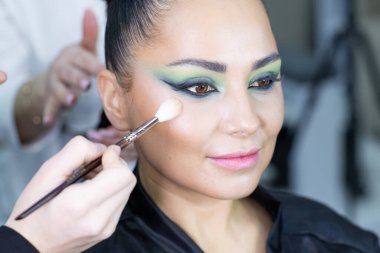 Modern bir güzellik salonu, güzellik, cazibe ve zarafet konseptinde profesyonel bir makyöz tarafından sanatsal makyaj yaptıran güzel Avrupalı bir kadın..