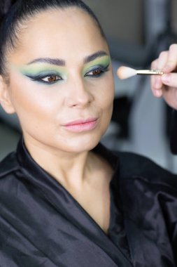 Modern bir güzellik salonu, güzellik, cazibe ve zarafet konseptinde profesyonel bir makyöz tarafından sanatsal makyaj yaptıran güzel Avrupalı bir kadın..