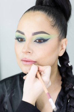 Modern bir güzellik salonu, güzellik, cazibe ve zarafet konseptinde profesyonel bir makyöz tarafından sanatsal makyaj yaptıran güzel Avrupalı bir kadın..