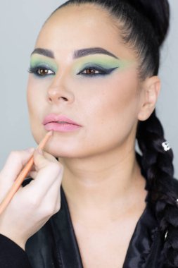 Modern bir güzellik salonu, güzellik, cazibe ve zarafet konseptinde profesyonel bir makyöz tarafından sanatsal makyaj yaptıran güzel Avrupalı bir kadın..