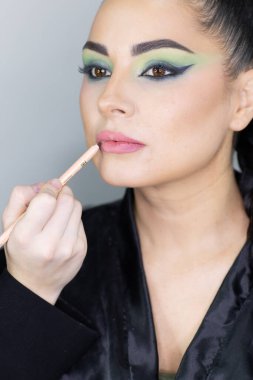 Modern bir güzellik salonu, güzellik, cazibe ve zarafet konseptinde profesyonel bir makyöz tarafından sanatsal makyaj yaptıran güzel Avrupalı bir kadın..