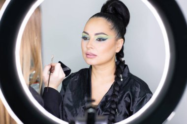 Beautiful European woman getting artistic makeup applied by a professional makeup artist in a modern beauty salon, beauty, glamour and elegance concept.