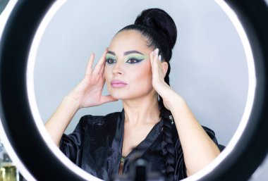 Beautiful European woman getting artistic makeup applied by a professional makeup artist in a modern beauty salon, beauty, glamour and elegance concept.