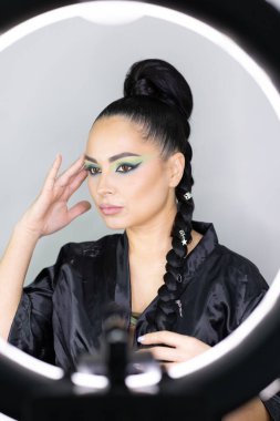 Beautiful European woman getting artistic makeup applied by a professional makeup artist in a modern beauty salon, beauty, glamour and elegance concept.