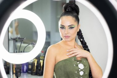 Beautiful European woman getting artistic makeup applied by a professional makeup artist in a modern beauty salon, beauty, glamour and elegance concept.