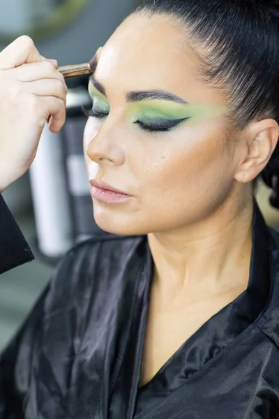 Modern bir güzellik salonu, cazibe ve zarafet konseptinde profesyonel bir makyöz tarafından sanatsal makyaj yaptıran güzel Avrupalı bir kadın..