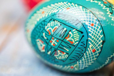 Geleneksel dekoratif desenleri ve canlı renkleri olan el yapımı Paskalya yumurtası. Temiz bir arkaplanda bayram sembolü, bahar, kutlama, halk sanatı, kültür mirası ve bayram geleneklerini temsil ediyor..