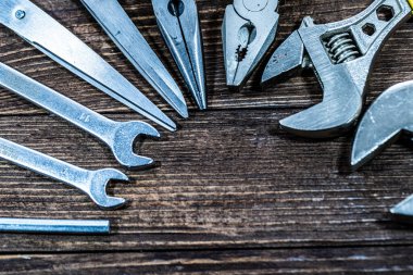 Ahşap bir arka planda düzenlenmiş ev yapımı ve onarım aletleri. Cilt, pense, civata, çekiç, makas, elektrik bandı ve DIY projeleri, ev geliştirme, yenileme, bakım ve atölye kavramları için gerekli el aletlerini içerir.