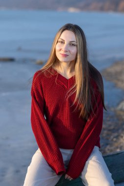Beautiful Woman in Rain Trench Coat Sitting on a Small River Boat, Ready to Leave, Thoughtful and Depressed Woman Meditating by the Lake Shore, Emotional and Contemplative Mood in Nature