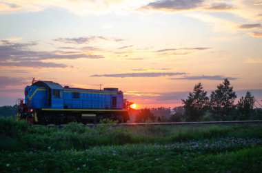 Sahanın üzerinde güzel bir gün batımı ve arka planda tren.