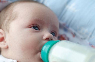 Bebek bir fincan süt yiyor.