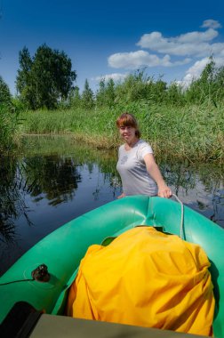 Kadın şişme tekneyi nehirden çekiyor.