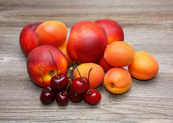 Нектарини, вишні та абрикоси на дерев'яному столі — стокове фото