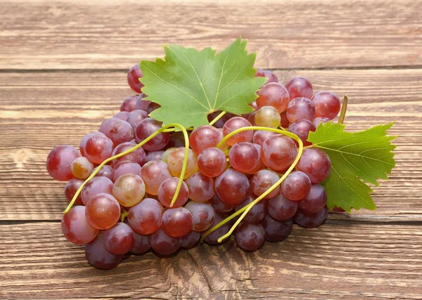 Uvas con hojas sobre mesa de madera —  Fotos de Stock