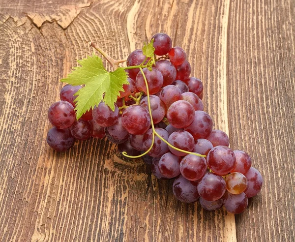 Uva con foglie su tavolo di legno — Foto Stock